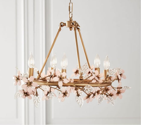 A gold nursery chandelier decorated with pink flowers