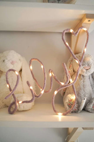 A knit name sign with twinkle lights that spell "Lily" in script