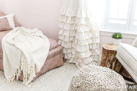 Baby nursery with layers of different textures in the rug, furniture, and window treatment