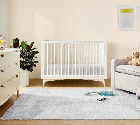 A pale gray washable nursery rug in a baby's room