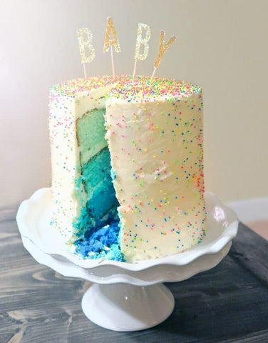 White frosted gender reveal cake with ombre blue sponge inside.