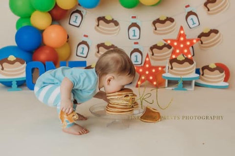 Baby eating stack of pancakes for birthday.