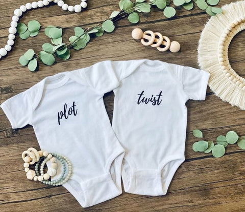 Baby onesies that say "Plot" and "Twist"