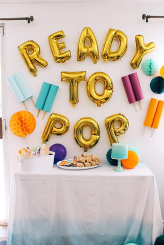 Balloons that spell "ready to pop" hung along with popsicle decorations