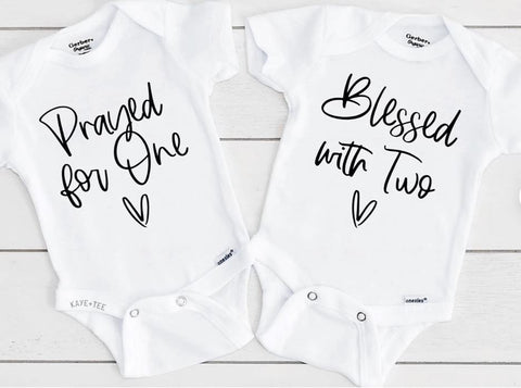 Baby onesies that say "Prayed for One" and "Blessed With Two"