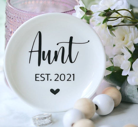 A pregnancy announcement jewelry dish that says "Aunt EST 2021"