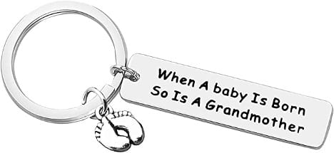 A pregnancy announcement keychain that says "when a baby is born, so is a grandmother"