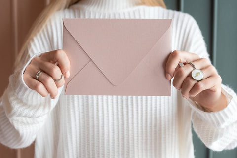 A woman holds a sealed envelope which contain a handwritten pregnancy announcement note