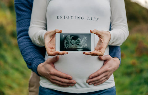 A couple shows off their ultrasound photo in a Father's Day pregnancy announcement