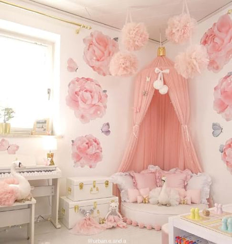 Pink toddler bedroom with pink bed canopy and floral wallpaper.