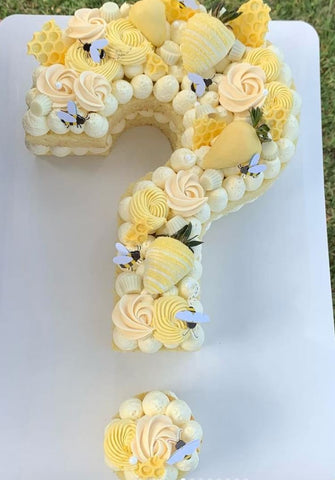 Question-mark-shaped bee-themed gender reveal cake. 