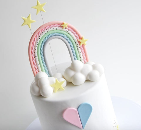 Gender reveal cake with pastel rainbow cake topper.