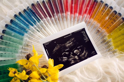 Ultrasound displayed with rainbow-colored needles to announce an IVF pregnancy