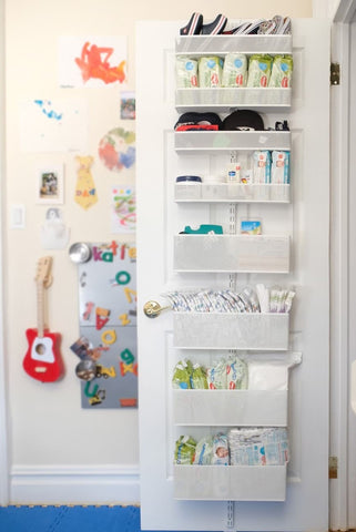 Hanging shelves filled with nursery essentials on the back of a door