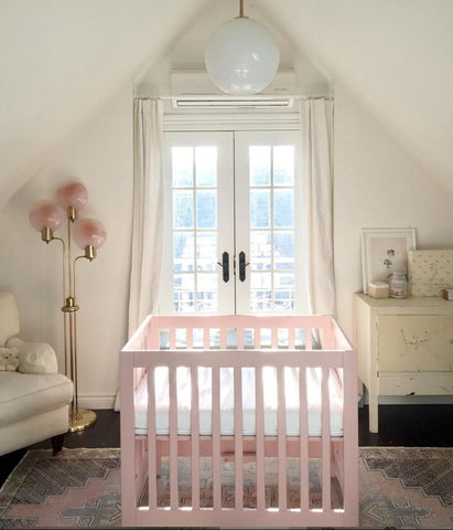 Pink mini crib in a baby nursery.