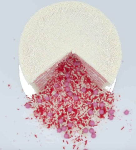 A sliced gender reveal cake that's spilling pink and red sprinkles.