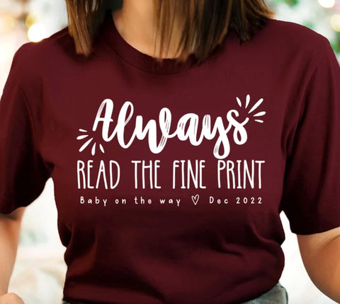 T-shirt that says "Always read the fine print" with pregnancy announcement written beneath it