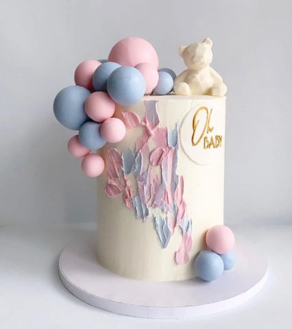 Gender reveal cake with white teddy bear cake topper.
