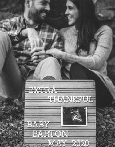 Couple poses behind a letterboard announcing pregnancy