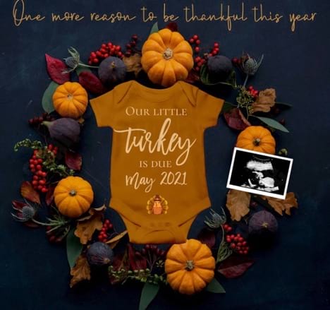 Baby onesie that says "Our little turkey due May 2021" arranged with fall decor