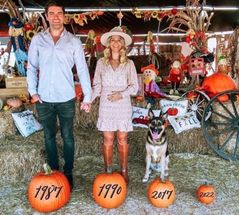 Family photo announcing pregnancy with pumpkins