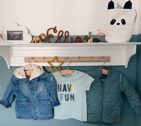 Clothing hooks in a toddler room that hold toddler-sized jackets and t-shirts.