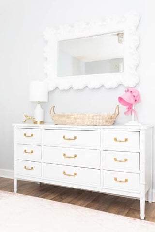 White dresser with gold hardware in an all-white baby room