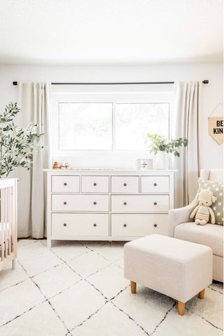 White nursery with white dresser, glider, and rug