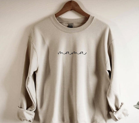 A beige sweatshirt that says "Mama" used in a winter pregnancy announcement