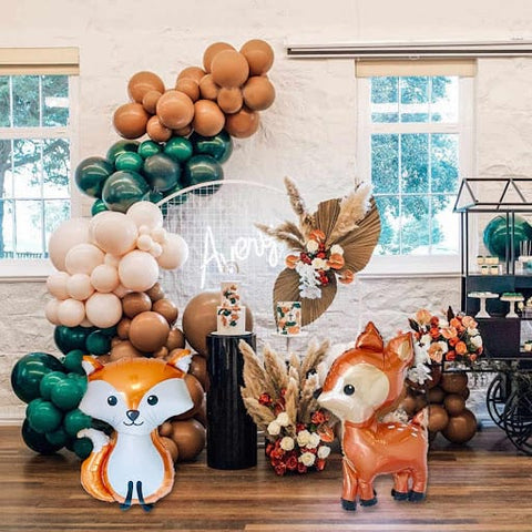 Emerald green, cream, brown, and fox and deer balloons on display for a fall baby shower