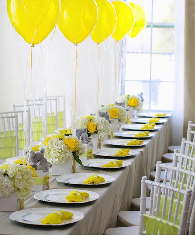 Table decorated with yellow balloons and yellow napkins folded like bowties