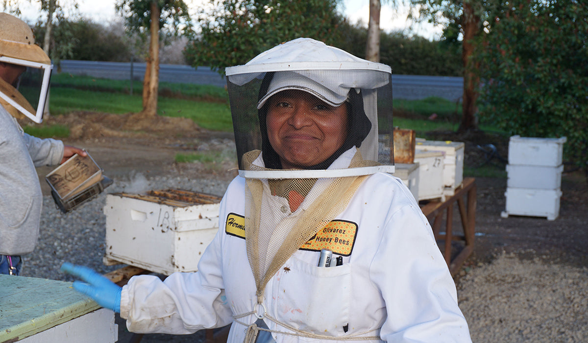 a beekeeper smiles at the camera outside