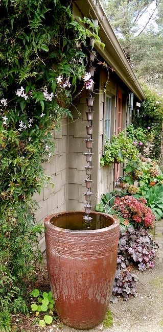 Rain Chain hanging from a gutter into a rain barrel. 