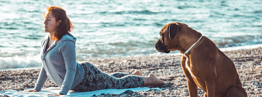 Woman on the beach with Yoga mat and dog 