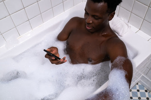 Man in a bathtub browsing his phone 