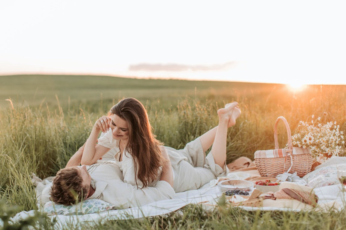 Man and woman lounging around with a picnic basket on grass