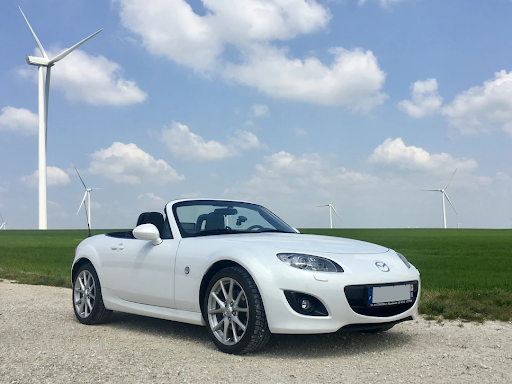 Image of the 1990 Mazda MX-5 Miata on the road with windmills