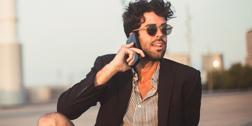 Man in torn jeans and a black blazer speaking on phone 