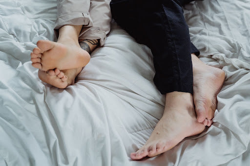  Image with legs of a man and woman in a bed 