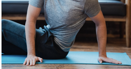 Man on Yoga mat twisting with palms on the mat for support 