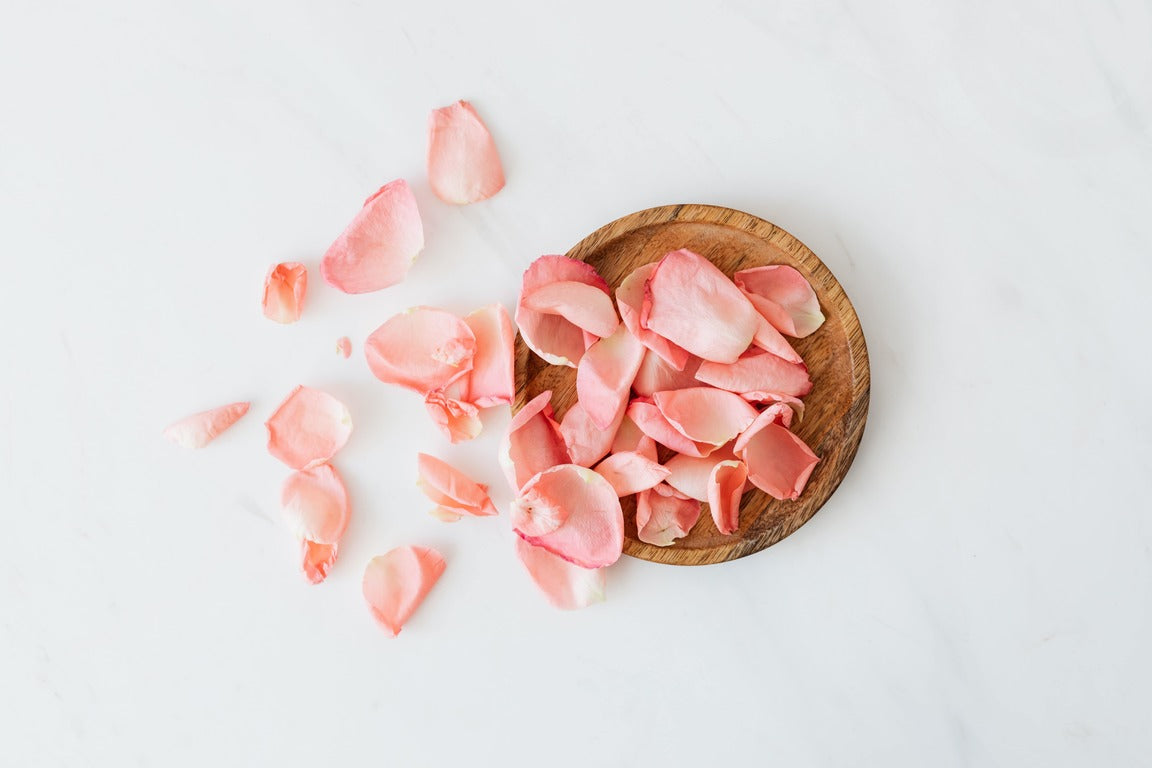 Rose petals falling from a basket against a white background 