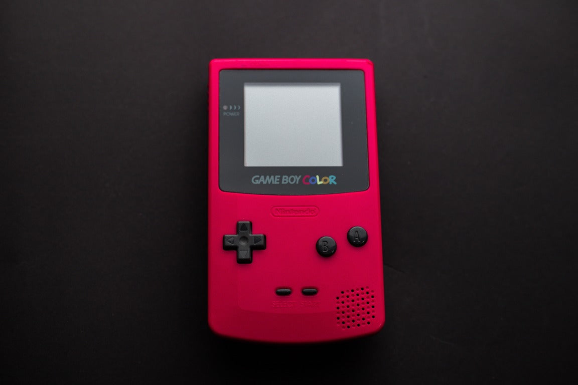 White Nintendo Game Boy with buttons in black, pink and grey colors 