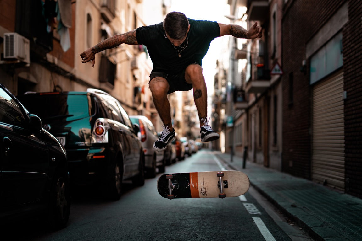 Man flipping a skateboard in a busy street