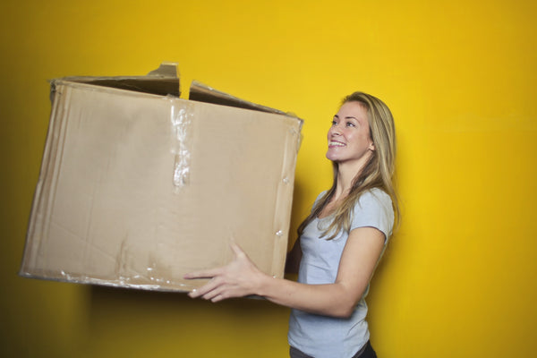 women smiling moving a cardboard box moving house home