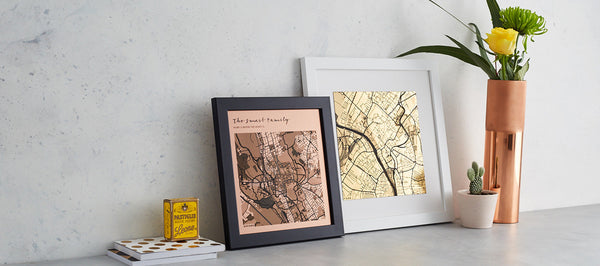 gold and bronze engraved maps leaning on a grey table and grey wall