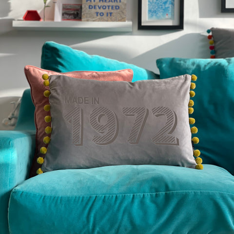 Grey personalised made in year cushion on a turquoise sofa. Engraved with the year 1972