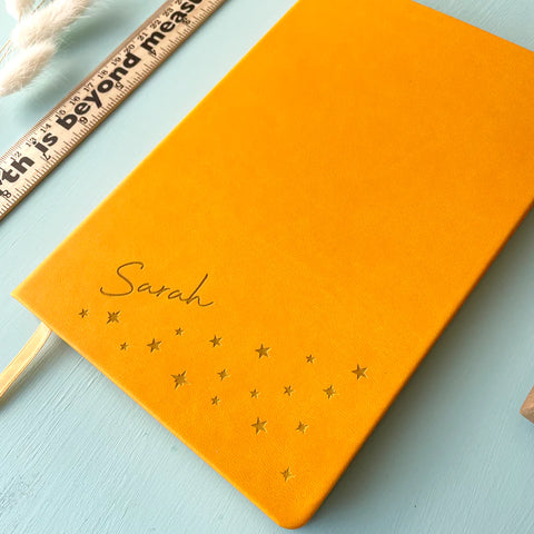 yellow personalised notebook engraved with stars at the bottom and a name