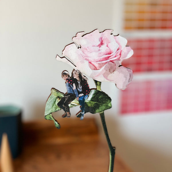 Siblings sitting together on a leaf of a bespoke pink wooden rose gift