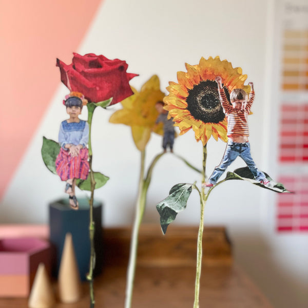 Single stems of wooden flowers with small children positioned on leaves