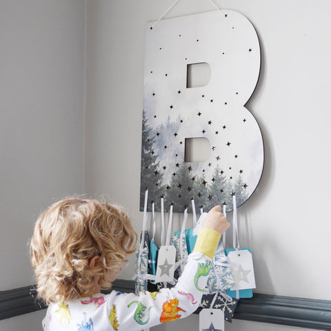 Large letter B with advent calendar gifts hanging from the bottom. Small curly haired boy is reaching for one gift